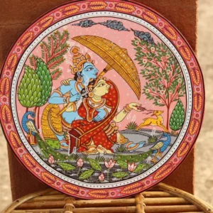 Hand-painted decorative wall plate with two figures under golden canopy, peacock, deer, lotus flowers, and intricate geometric borders in pink, blue, red, and g