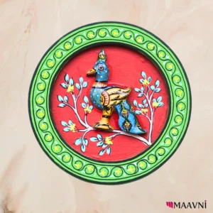 Circular decorative wall plate with bright red field, lime green scroll border, and three-dimensional painted bird figure in blue and gold with floral branches
